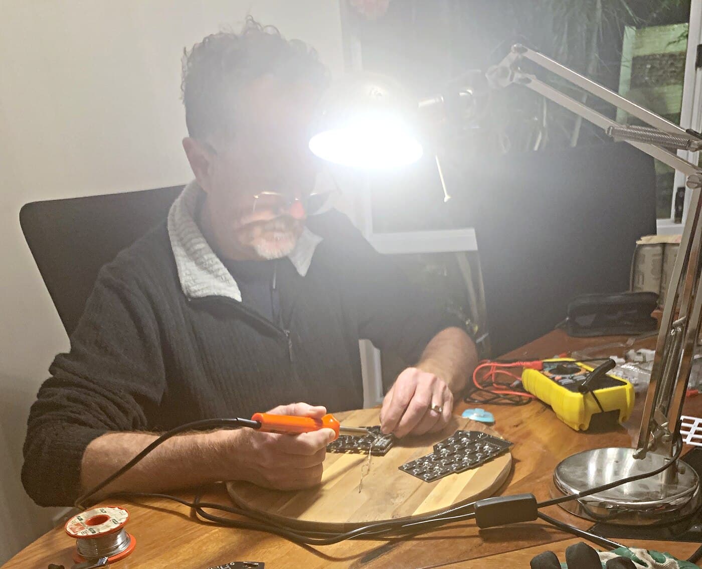 Soldering onto a Corne PCB at the workbench, with a solder spool and multimeter alongside